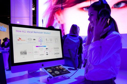 SK텔레콤 모델이 SK텔레콤-SM엔터테인먼트 공동 부스에 전시된 'AI 기반 음원 분리 기술'을 체험하고 있다. SK텔레콤 제공